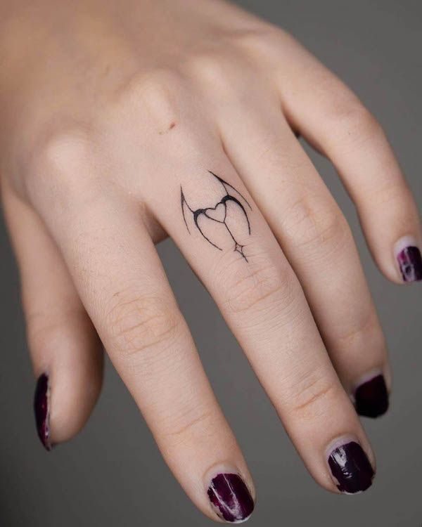 Cartoon devil tattoo on middle finger